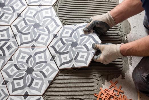 professional tiler installing patterned hexagonal floor tiles using cement adhesive photo